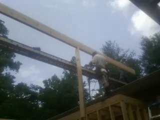 Carpenter setting a ridge beam over a new addition frame — Ice Dam Removal by Roofing Brothers in Belding