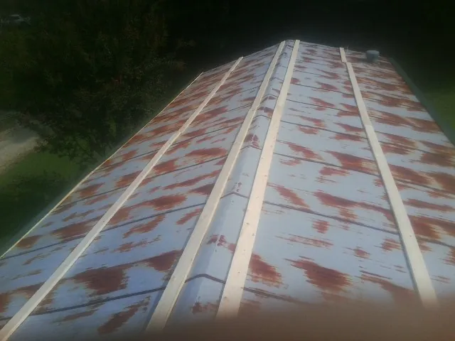 Rusted metal roof panels with new wood purlins before replacement — Storm Damage Roof Repair in Belding by Roofing Brothers