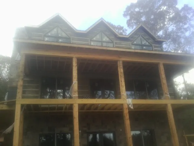 Dormers and porch framing on a large log home under construction — Roof Coating work by our crew in Belding