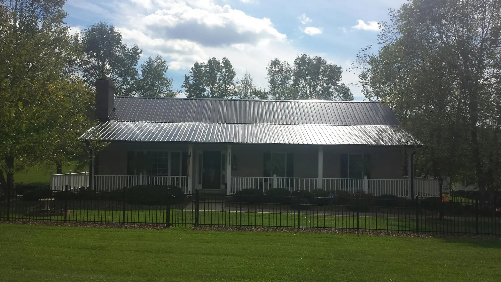 Gray metal roof on a brick ranch with a full width front porch — Gutter Guard Installation work by our crew in Belding